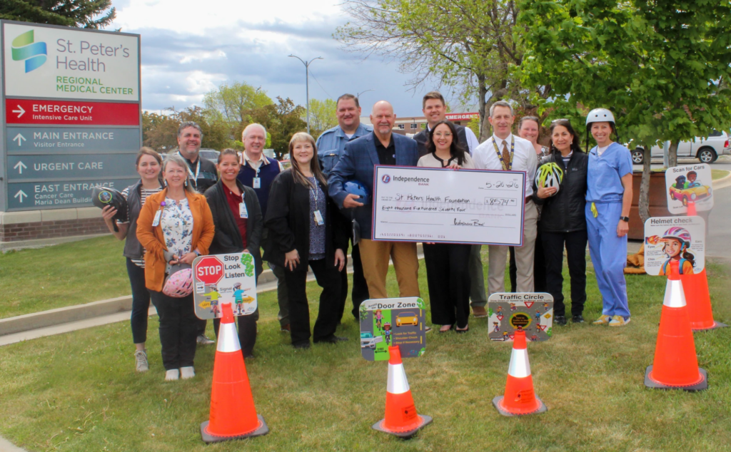 Group of hospital staff and donors posing outdoors with a large ceremonial check in front of St. Peter's Health, celebrating a donation.